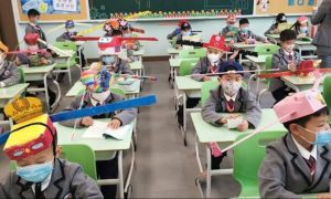 Παιδιά στη Χανγκτσόου φορούν καπέλα κοινωνικής αποστασιοποίησης με το που επιστρέφουν στο σχολείο